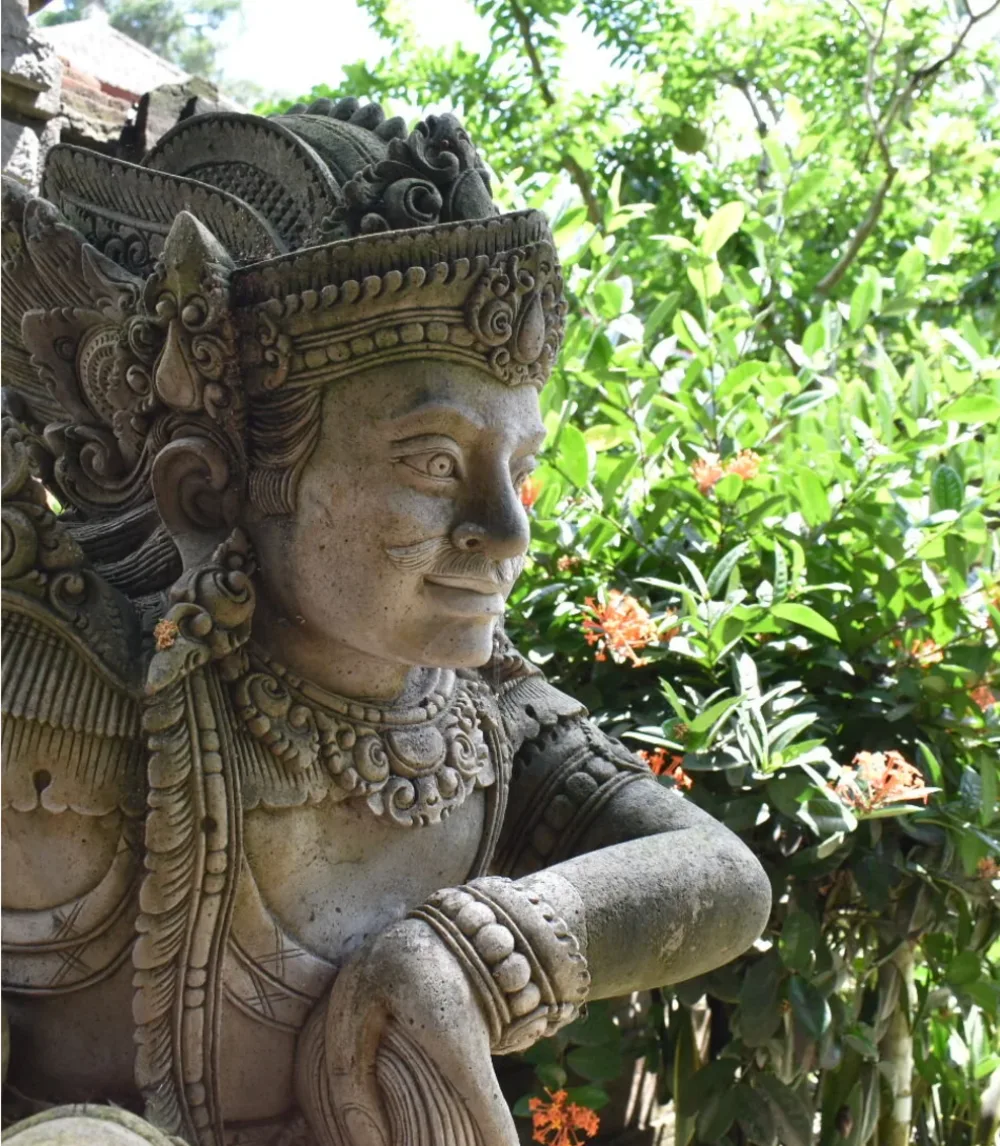 Balinese temple statue among lush greenery
